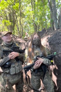 two people in camouflage outfits standing next to each other in the woods