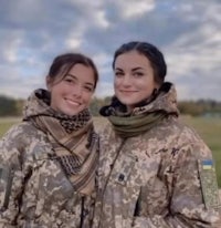 two women in camouflage outfits posing for a photo