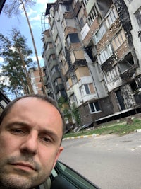 a man taking a selfie in front of an apartment building