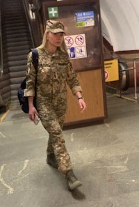 a woman in a camouflage uniform walking down an escalator