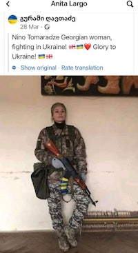 a woman in ukraine poses with an AK-47